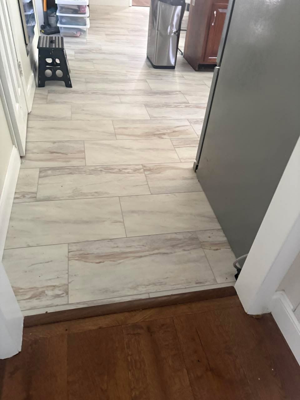 Light wood-look tile flooring installation through a kitchen walkway