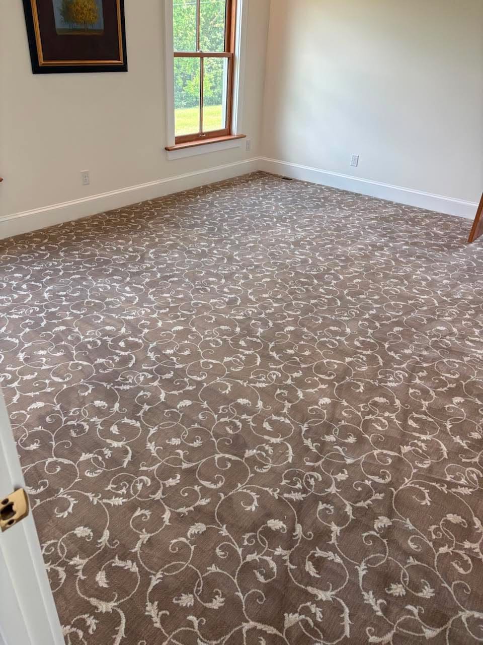 Patterned carpet installation in a formal room with wood-trimmed windows